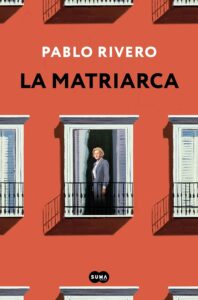 "Portada del libro 'La Matriarca' de Pablo Rivero, mostrando una mujer mayor de pie en un balcón, con un edificio de fachada roja y ventanas blancas.