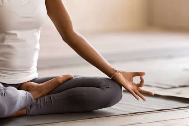 Persona practicando yoga en postura de meditación con un gesto de mano mudra.